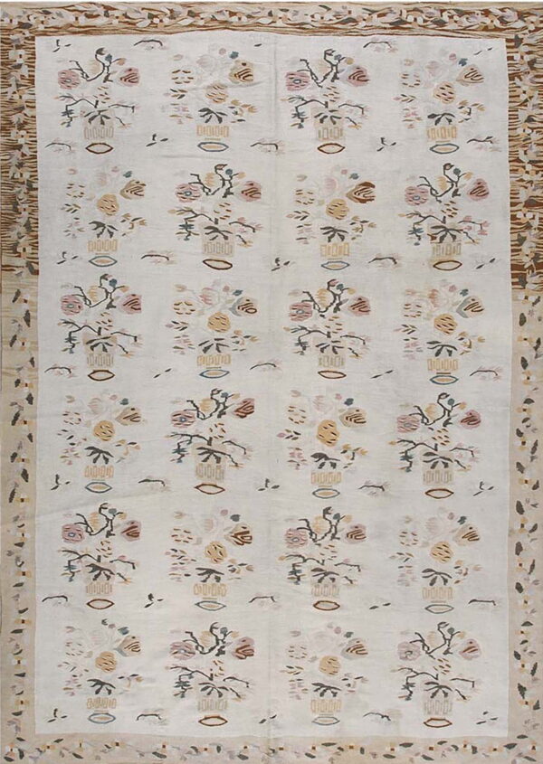 Off-white rug with repeating pastel floral vase patterns and complex geometric side borders in brown and cream.