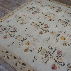 Low-pile cream rug with soft pastel floral designs and a beige border rests on weathered wood.