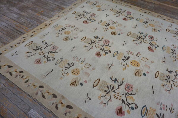 Low-pile cream rug with soft pastel floral designs and a beige border rests on weathered wood.