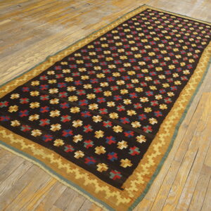 Flatweave rug, dark brown field with red, blue, and gold crosses, and a stepped geometric border.