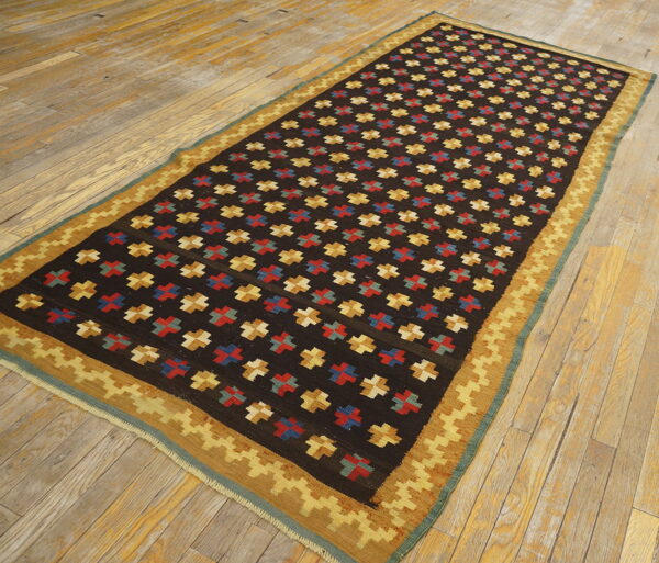 Flatweave rug, dark brown field with red, blue, and gold crosses, and a stepped geometric border.