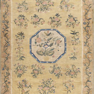 A gold rug with pink and blue floral bouquets, an octagonal medallion, and botanical vine borders.