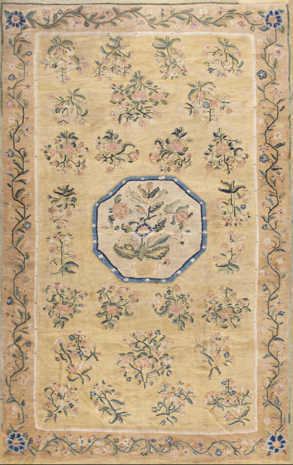 A gold rug with pink and blue floral bouquets, an octagonal medallion, and botanical vine borders.