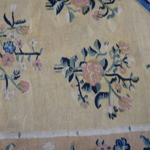 Pale yellow rug featuring scattered pink, navy, blue, and green floral vine motifs and a tan border.