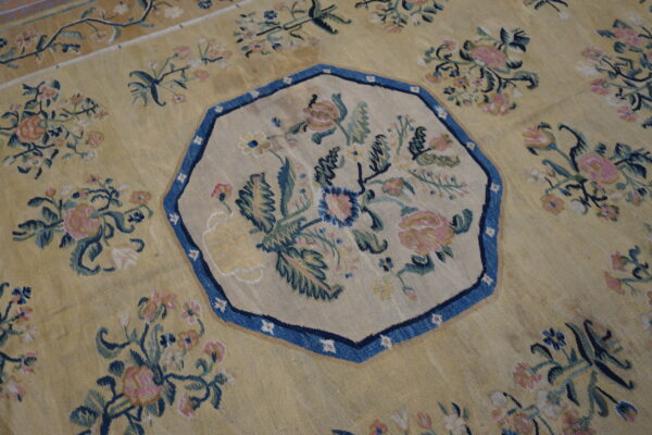 Ornate yellow rug with an octagonal blue-bordered medallion centered with pink and green floral bouquets.