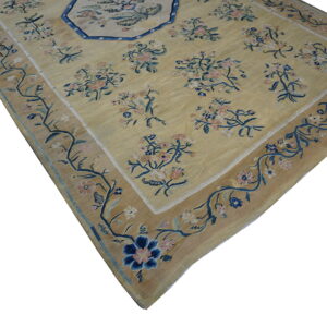 Muted yellow rug with pink and navy floral sprays and an octagonal blue-outlined central design.