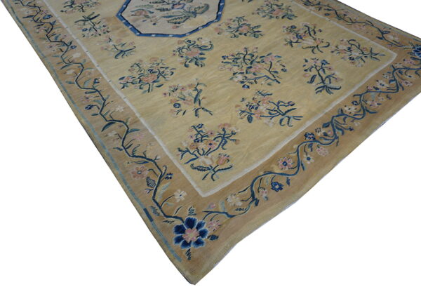 Muted yellow rug with pink and navy floral sprays and an octagonal blue-outlined central design.