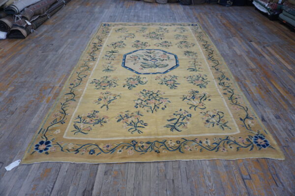 Pale yellow rug with blue and pink floral motifs and medallion on distressed gray hardwood floors.