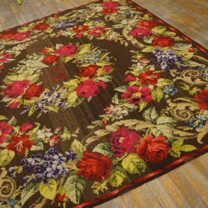 Brown rug with a dense floral wreath of red, pink, and purple flowers on aged wooden floors.