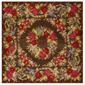 Dark brown needlepoint rug featuring a dense floral pattern with red roses, purple clusters, beige scrolls, and central initials.