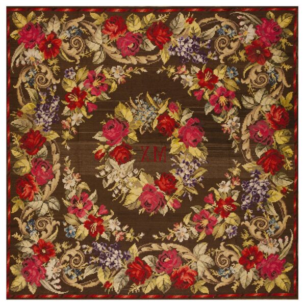 Dark brown needlepoint rug featuring a dense floral pattern with red roses, purple clusters, beige scrolls, and central initials.