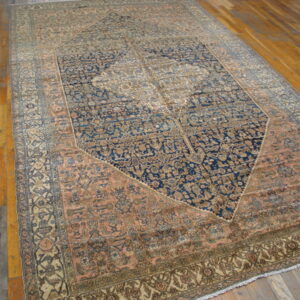 Large, low-pile rug with blue, rose, and beige traditional patterns covers glossy wood flooring.