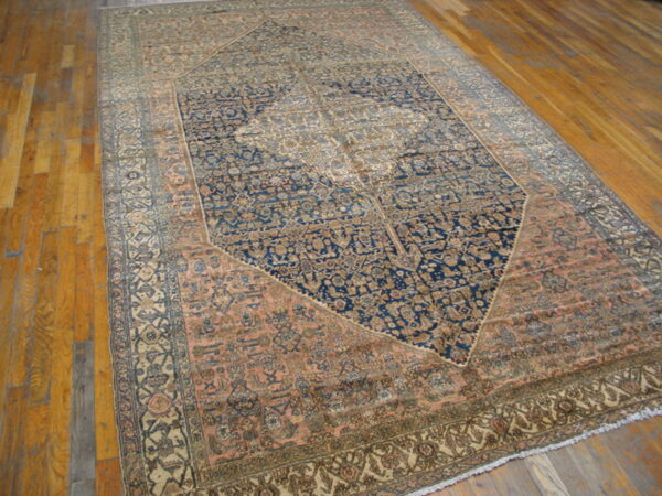 Large, low-pile rug with blue, rose, and beige traditional patterns covers glossy wood flooring.