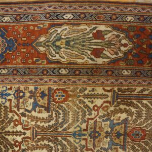 Ornate rug border in terracotta, blue, and cream sits on distressed yellow and gray wood planks.