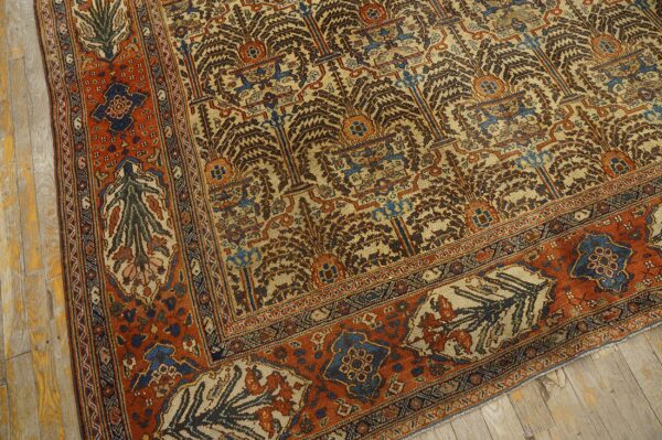 Intricate beige and brown tree-of-life rug with wide orange and blue geometric borders on wood flooring.