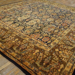 Traditional rug displaying detailed floral patterns in navy blue, gold, and muted brown on rustic plank floor.