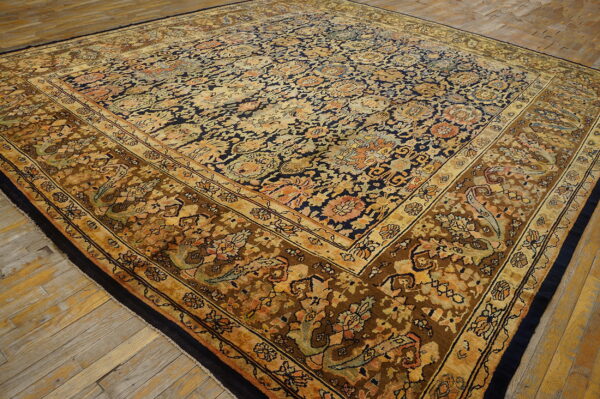Traditional rug displaying detailed floral patterns in navy blue, gold, and muted brown on rustic plank floor.