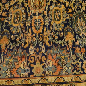 Close-up of a navy rug field and gold border with dense floral designs in orange and green.