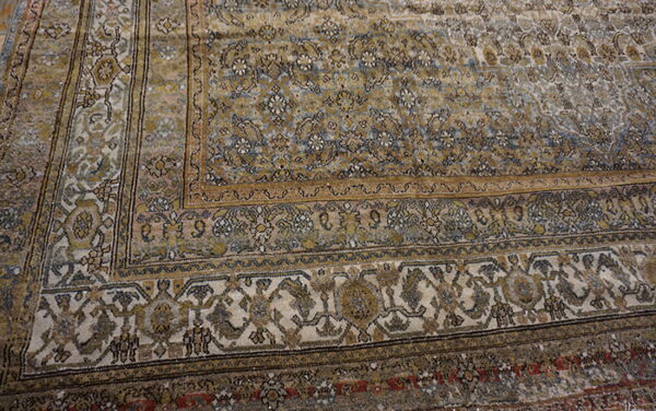Distressed rug featuring intricate gold, dusty blue, and cream traditional patterns and layered borders.