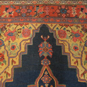 Detailed view of a rug featuring navy blue, mustard yellow, and red with complex geometric floral motifs.