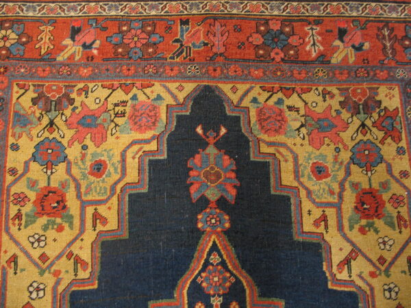 Detailed view of a rug featuring navy blue, mustard yellow, and red with complex geometric floral motifs.