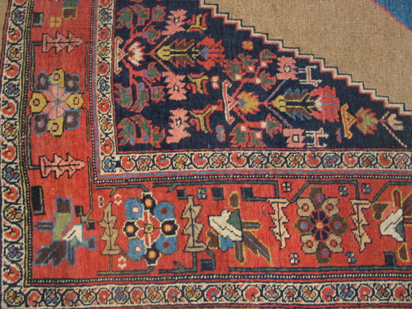 Navy and red patterned rug corner with complex borders meets a flat beige surface with a stepped edge.