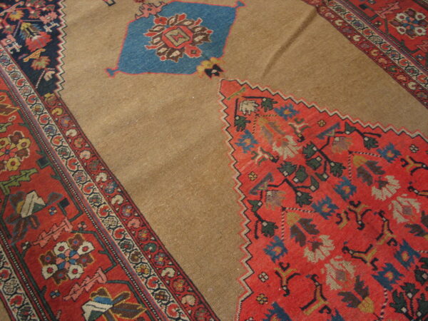 Traditional rug detail showing a camel-colored field contrasting with serrated red, blue, and multi-colored geometric motifs.