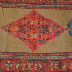 Tan rug center featuring a large, red, stepped diamond medallion bordered by intricate geometric designs and blue accents.