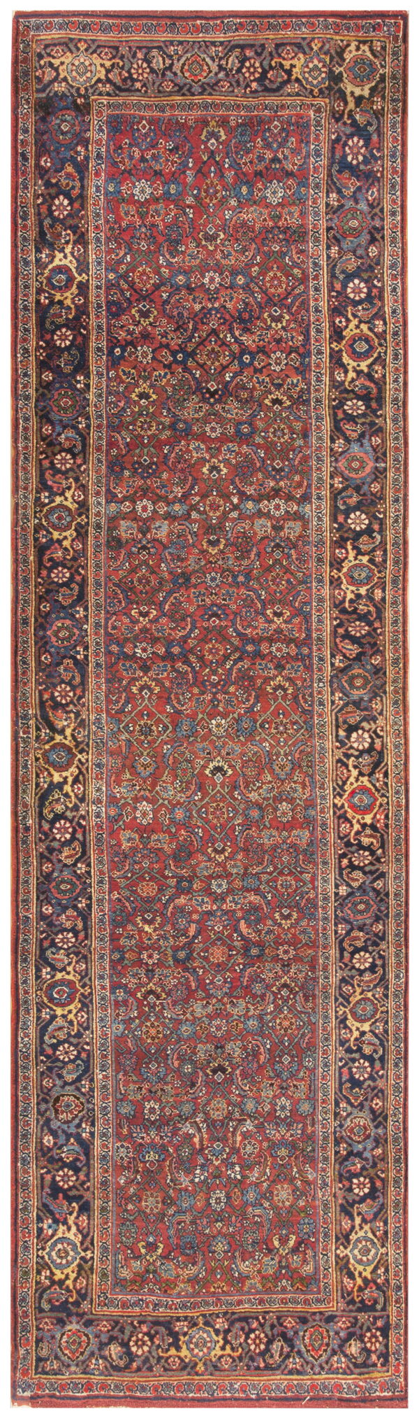 A narrow runner rug features a deep red, dense floral field surrounded by a wide navy patterned border.