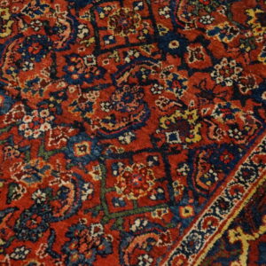 Detailed view of a deep red and navy rug with intricate geometric and stylized floral patterns.