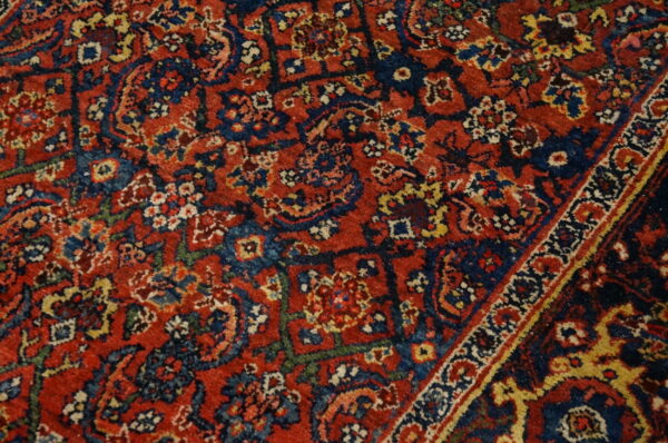 Detailed view of a deep red and navy rug with intricate geometric and stylized floral patterns.