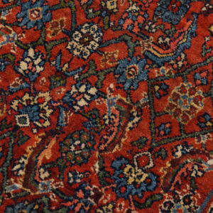 Close-up of a low-pile rug featuring a traditional floral pattern in red, blue, cream, and dark green.