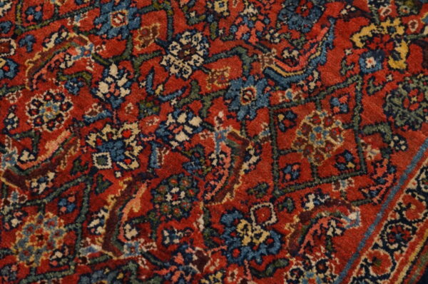 Close-up of a low-pile rug featuring a traditional floral pattern in red, blue, cream, and dark green.