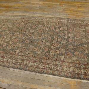 Muted runner rug with intricate floral designs in sage, rust, and cream on old wood planks.