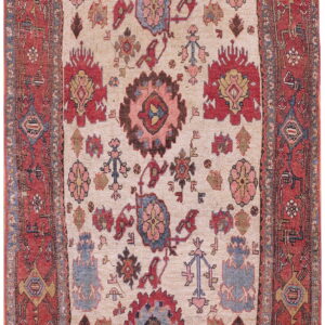 Low-pile rug with an ivory field and multicolored floral medallions within a wide red border.