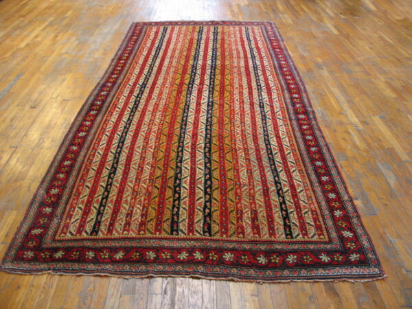 This low-pile rug features dense vertical stripes of red, gold, and dark blue on wood floors.
