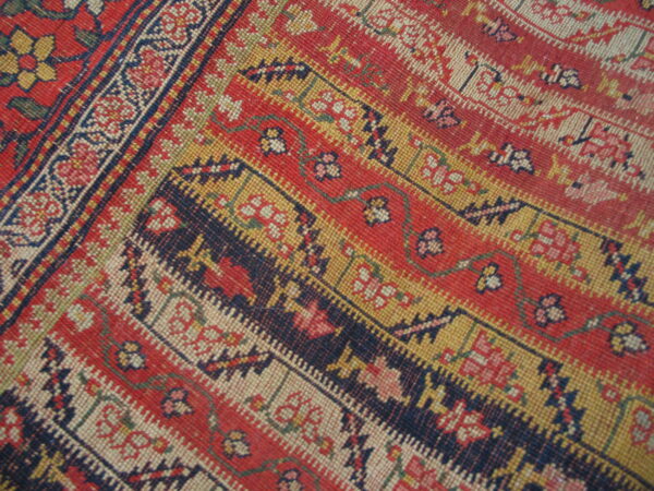 Intricate border pattern in red, navy, gold, and white with tightly woven low-pile texture.