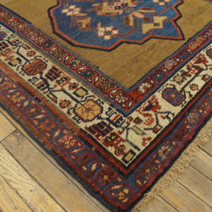 Brown rug featuring a large blue medallion and multicolored geometric borders on a wood floor.