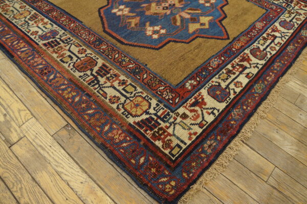 Traditional rug corner in camel, blue, red, and cream tribal patterns on wide plank wood floor.