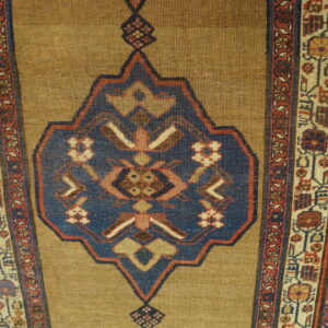 Elongated runner with a tan field, deep blue center medallion, and multi-banded red and cream borders on wood floor.