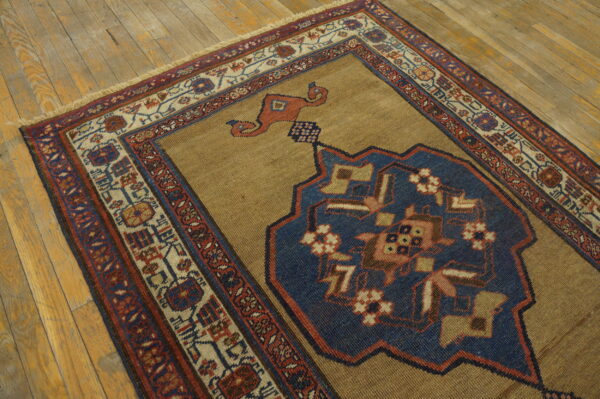 Camel rug with a striking blue geometric medallion and red borders on light hardwood planks.