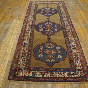 Camel and blue geometric runner rug with red borders lies on wide-plank wood flooring.