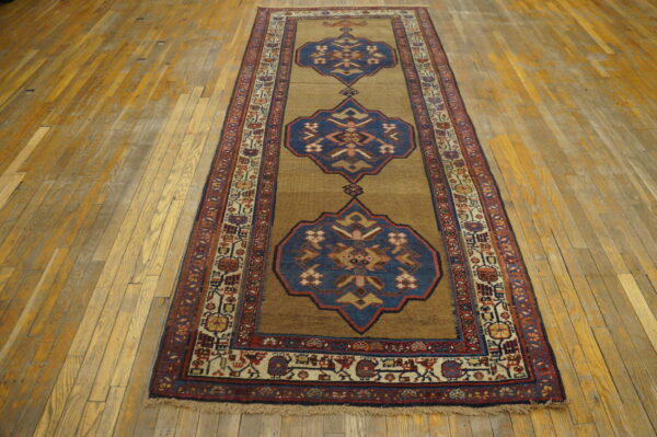 Camel and blue geometric runner rug with red borders lies on wide-plank wood flooring.