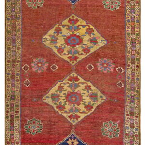 Rust red runner with four large diamond medallions in blue and gold, surrounded by a multicolored floral border.