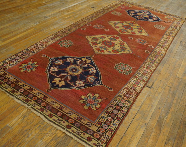 Red runner rug featuring navy and yellow geometric medallions displayed on light, distressed hardwood planks.