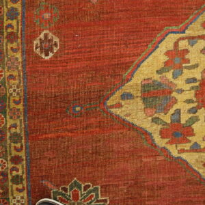 Red rug detail shows a large golden yellow medallion and multicolored geometric border on distressed wood planks.