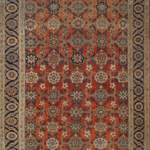 Orange rug with detailed blue and cream floral lattice pattern and a navy border on a wood floor.