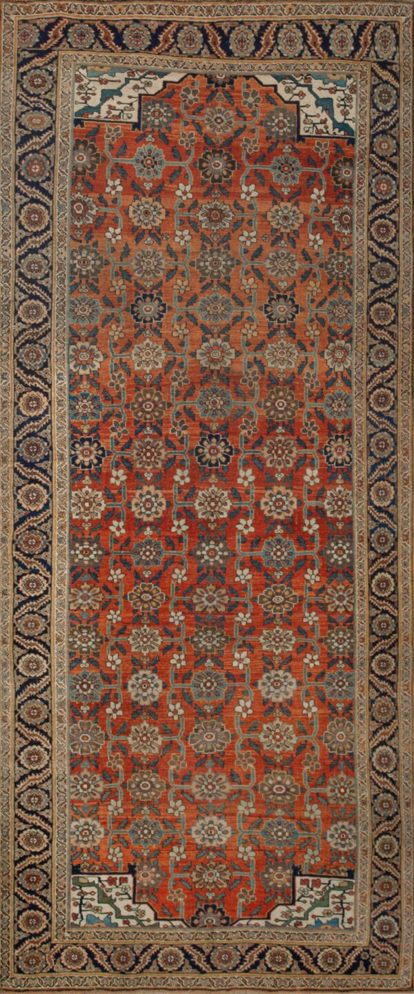 Orange rug with detailed blue and cream floral lattice pattern and a navy border on a wood floor.