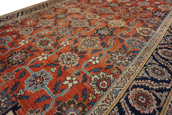 Rust red rug featuring an all-over traditional floral vine pattern in blue, navy, cream, and yellow.