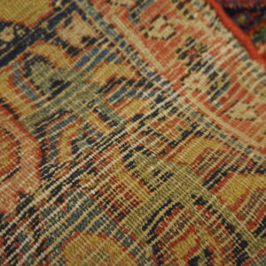 Tight flatweave pattern featuring interlocking geometric motifs colored tan, dark blue, green, and rust red.